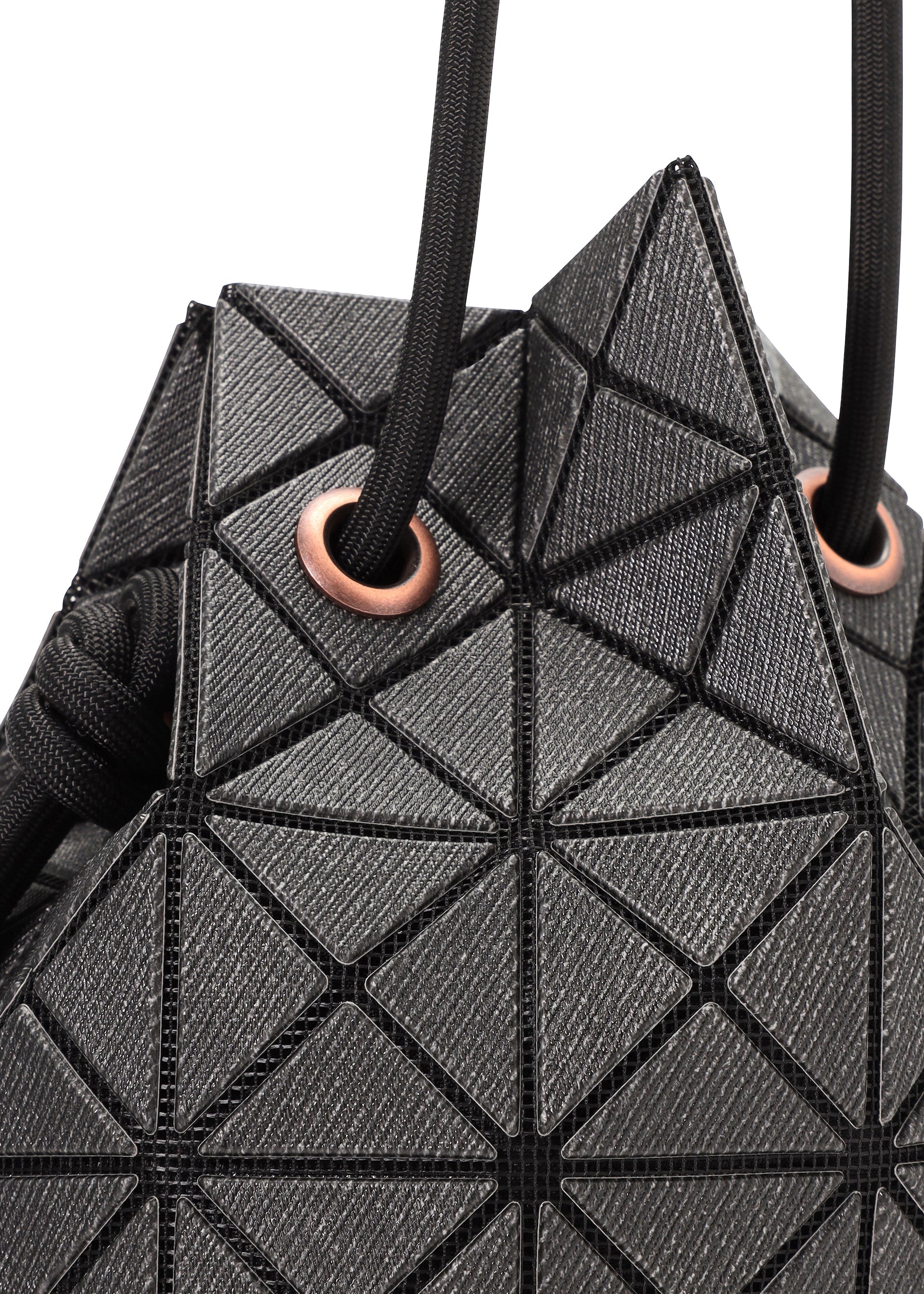 Zoomed view Close-up of the WRING DENIM bag by BAO BAO ISSEY MIYAKE, a black geometric drawstring bag with triangle patterns and black cords threaded through copper-toned metal eyelets.