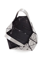 The CARAT by BAO BAO ISSEY MIYAKE is a geometric silver and black metallic handbag featuring angular panels, an open top, two sturdy handles, a black inner lining, and a convenient inner zippered pocket for added functionality.