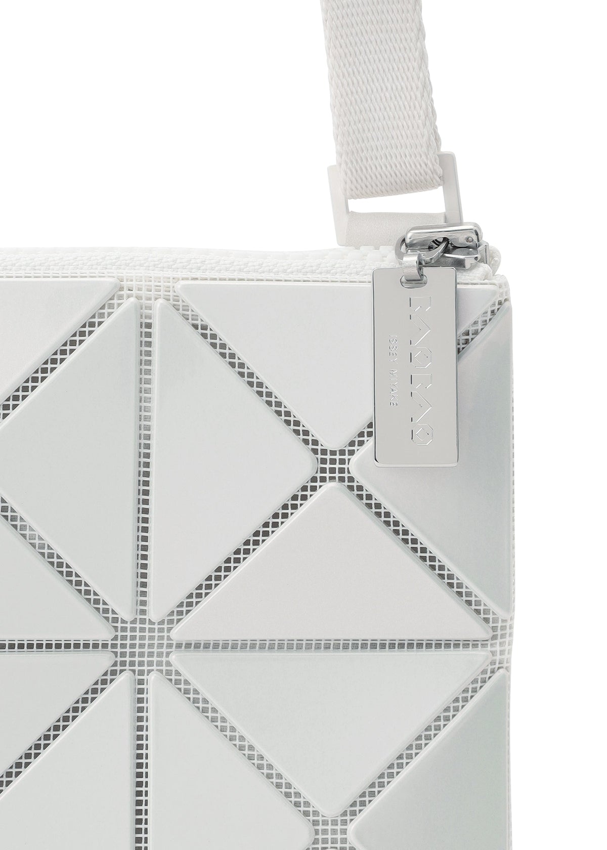 Close-up of the LUCENT METALLIC shoulder bag by BAO BAO ISSEY MIYAKE, featuring white enamel triangular panels, a visible strap and zipper, and a metallic tag on the pull. view 7 of 10