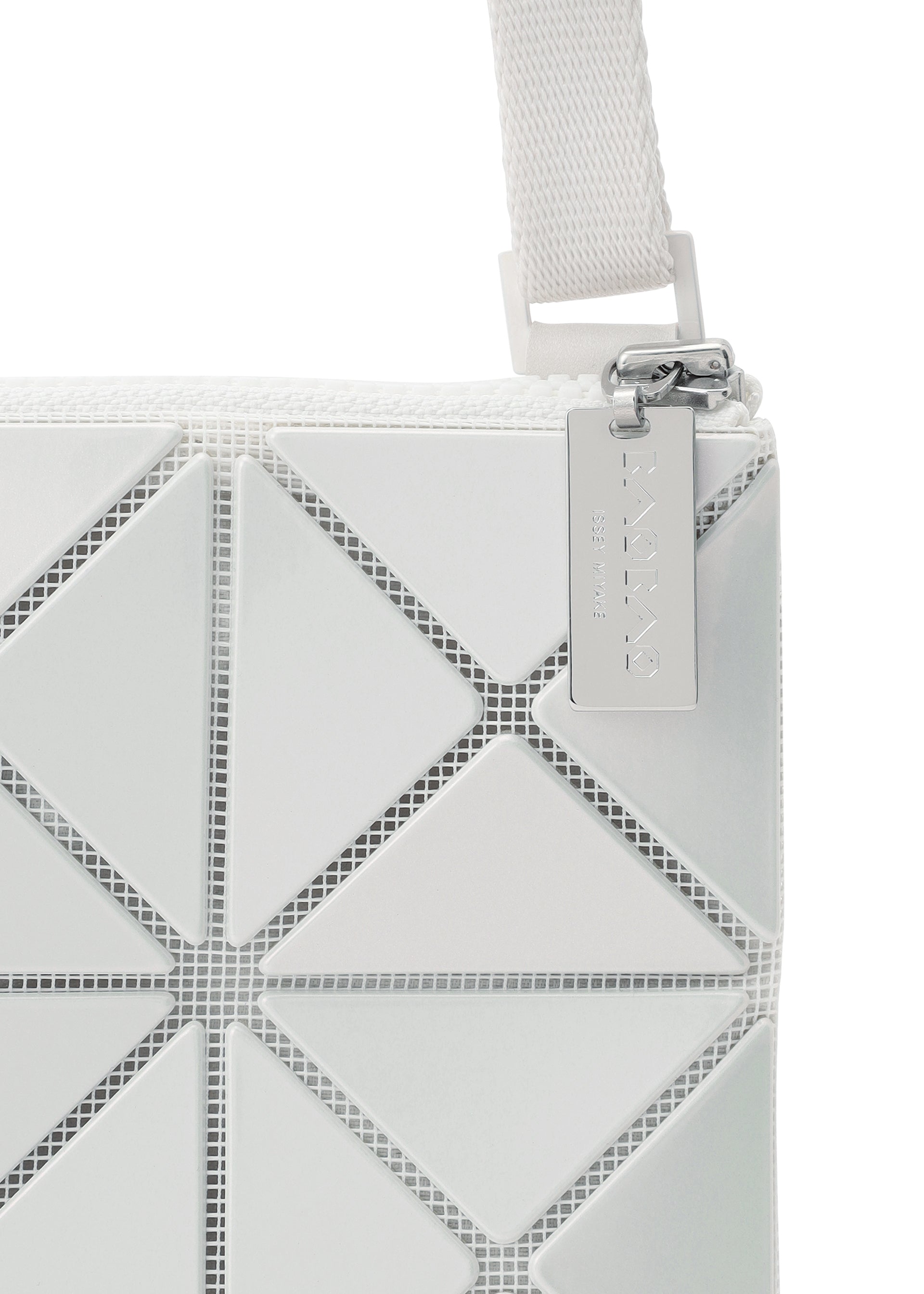 Zoomed view Close-up of the LUCENT METALLIC shoulder bag by BAO BAO ISSEY MIYAKE, featuring white enamel triangular panels, a visible strap and zipper, and a metallic tag on the pull.