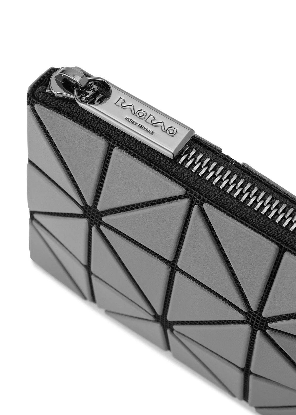 Close-up of the CASSETTE geometric-patterned gray zipper pouch by BAO BAO ISSEY MIYAKE, featuring black lines, a metallic zipper, and a branded zipper pull. view 5 of 6