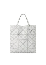 The BAO BAO ISSEY MIYAKE MAP tote bag is white with black triangular lines, features two handles and a minimalist design, and is displayed on a plain white background.