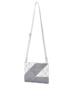 The SIGN shoulder bag by BAO BAO ISSEY MIYAKE features an adjustable strap and geometric design with white, light gray, and dark gray triangles on a rectangular surface, inspired by road sign motifs.