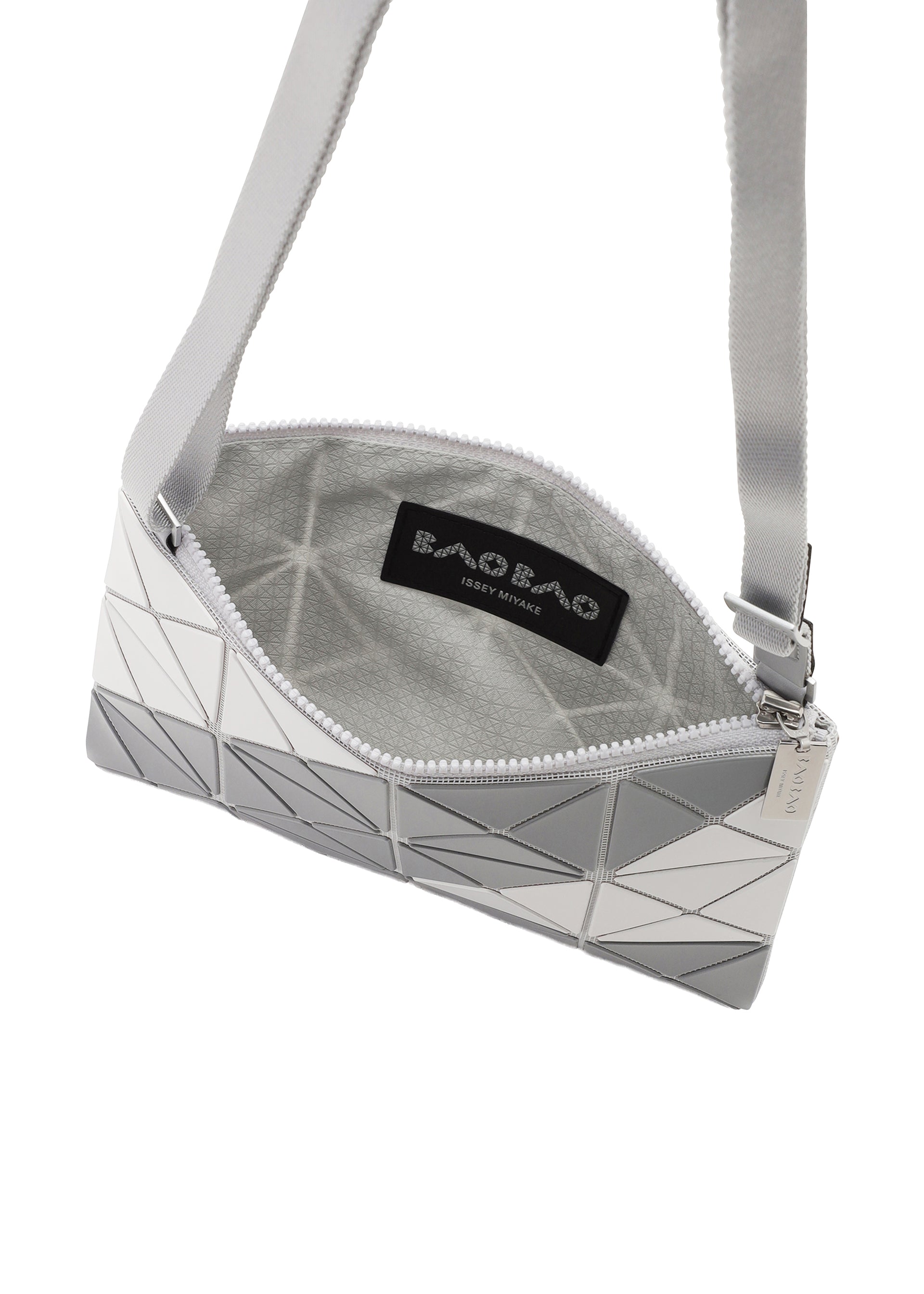 Zoomed view The SIGN crossbody by BAO BAO ISSEY MIYAKE features a geometric white and gray exterior with a road sign-inspired triangular tile pattern, zippered opening, gray interior, and an inner “BAO BAO ISSEY MIYAKE” label.