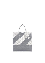 The SIGN tote bag by BAO BAO ISSEY MIYAKE features a gray and white geometric pattern with triangles, two white handles, a zippered inside pocket, and fits A4 documents—shown on a plain white background.