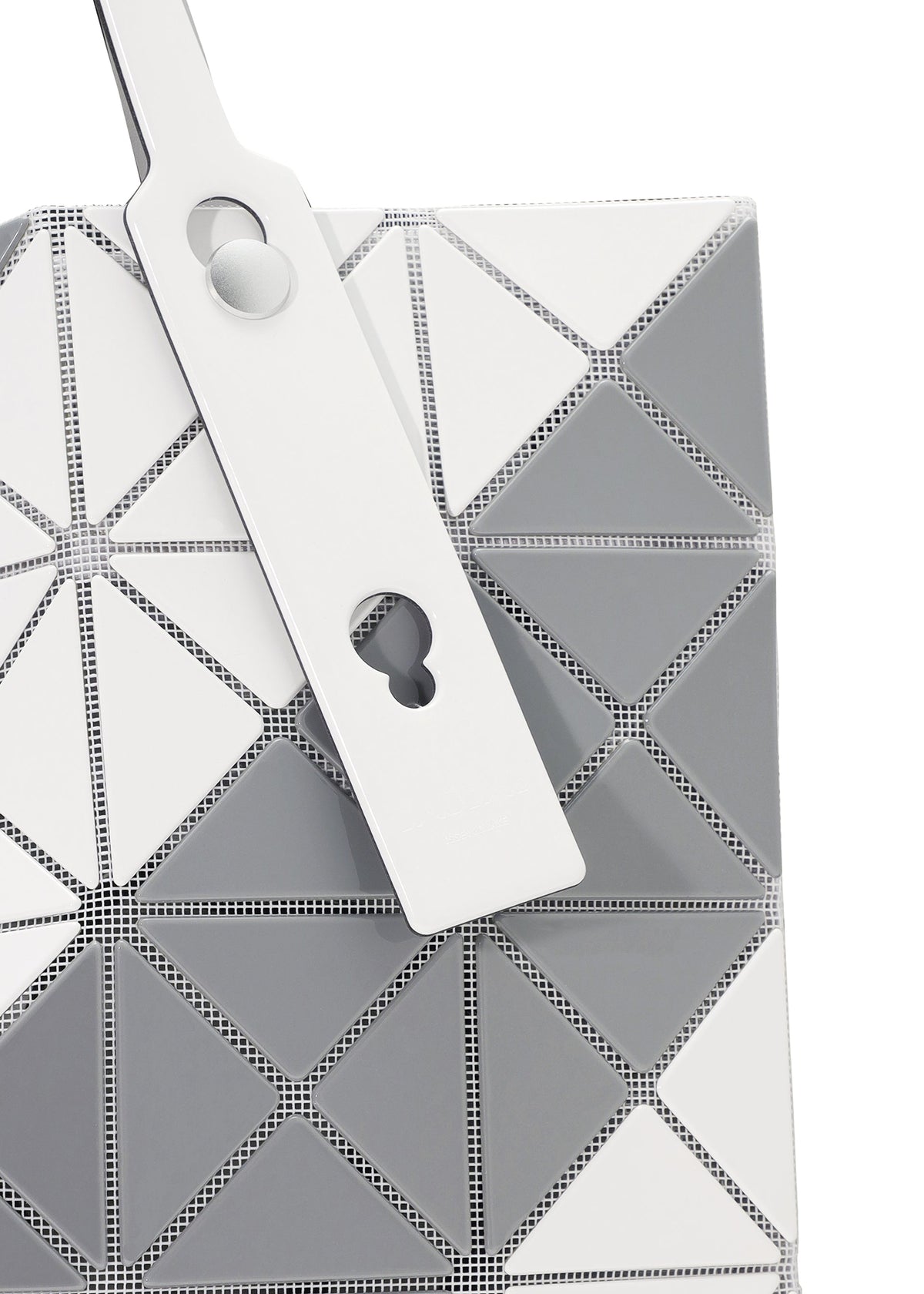 Close-up of the SIGN tote bag by BAO BAO ISSEY MIYAKE, featuring a geometric pattern in white, grey, and silver triangular panels with a white strap with circular and keyhole cutouts; fits A4-sized documents. view 4 of 6