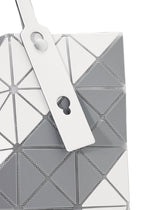 Close-up of the SIGN tote bag by BAO BAO ISSEY MIYAKE, featuring a geometric pattern in white, grey, and silver triangular panels with a white strap with circular and keyhole cutouts; fits A4-sized documents.