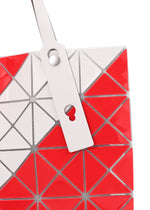 A close-up of the SIGN tote bag by BAO BAO ISSEY MIYAKE, featuring a red and white geometric triangular pattern and a tag with circular and keyhole cutouts—ideal for carrying A4 documents or a 13-inch laptop.