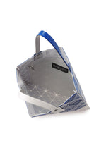 The SIGN tote by BAO BAO ISSEY MIYAKE features a geometric blue and white design, open top, spacious interior for A4 documents or a 13-inch laptop, zippered pocket, black BAO BAO label, and blue and white handles.