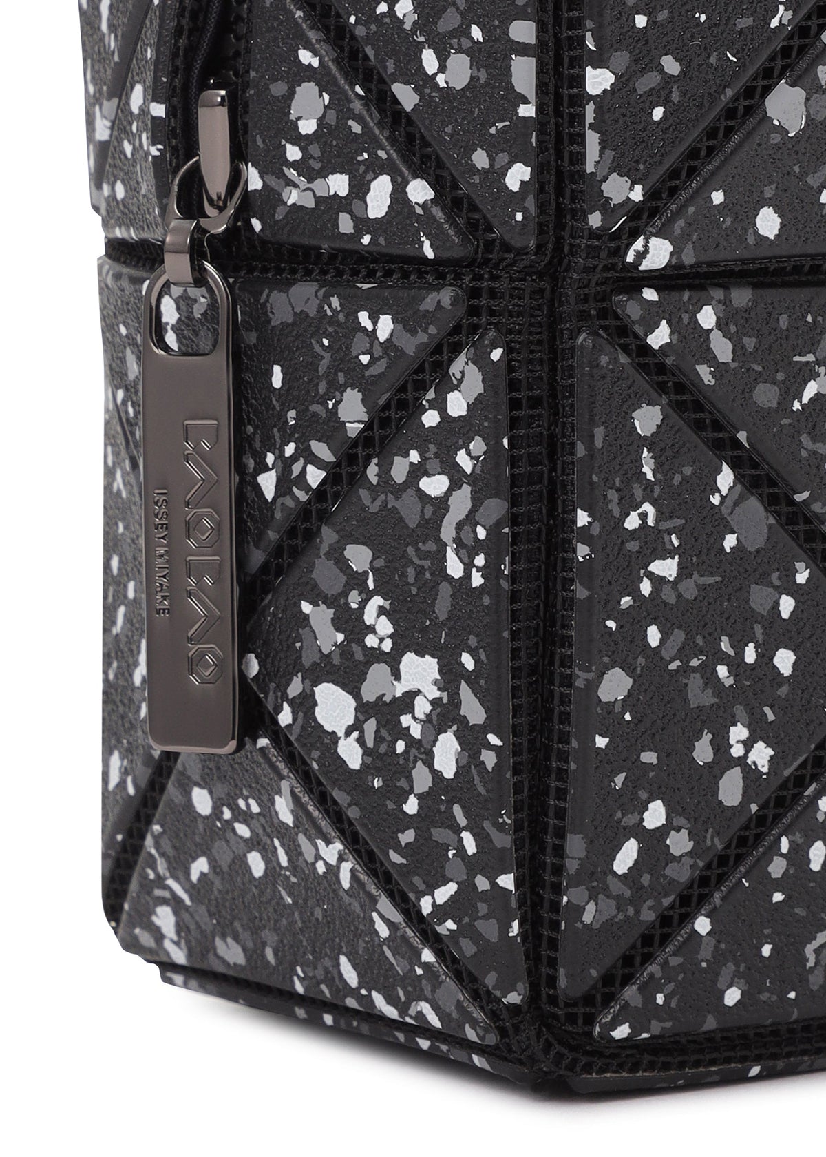 Close-up of the BAO BAO ISSEY MIYAKE CITY pouch featuring black geometric, leather-like triangular panels with a speckled white design and a metallic branded zipper pull, showcasing its signature modern style. view 6 of 8