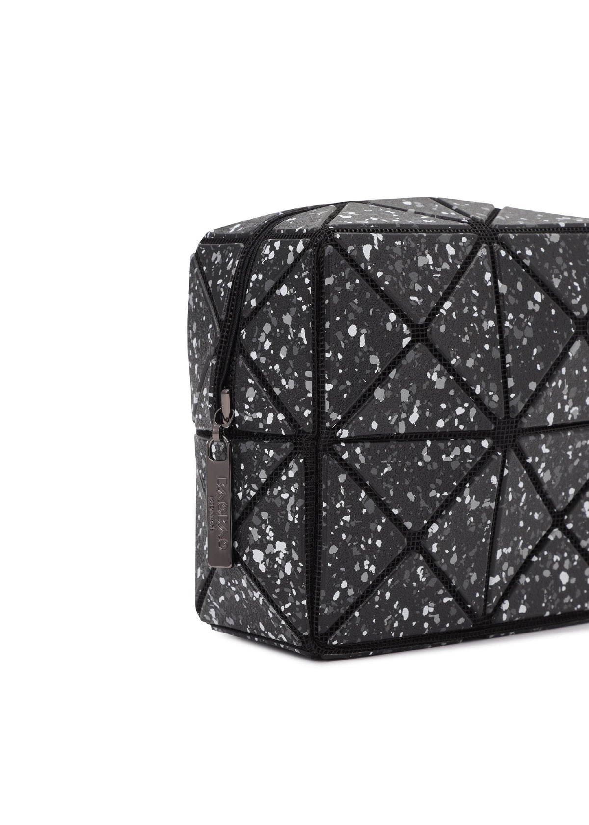 The CITY toiletry bag by BAO BAO ISSEY MIYAKE features black geometric panels with a speckled white and gray pattern, triangular stitching, a zip closure with metal tag, and a sturdy gusset—shown angled on a white background. view 7 of 8