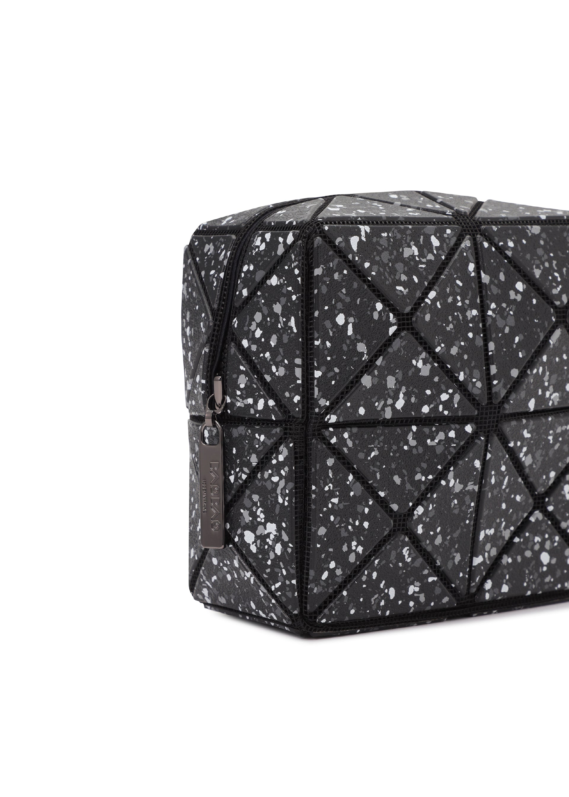 Zoomed view The CITY toiletry bag by BAO BAO ISSEY MIYAKE features black geometric panels with a speckled white and gray pattern, triangular stitching, a zip closure with metal tag, and a sturdy gusset—shown angled on a white background.