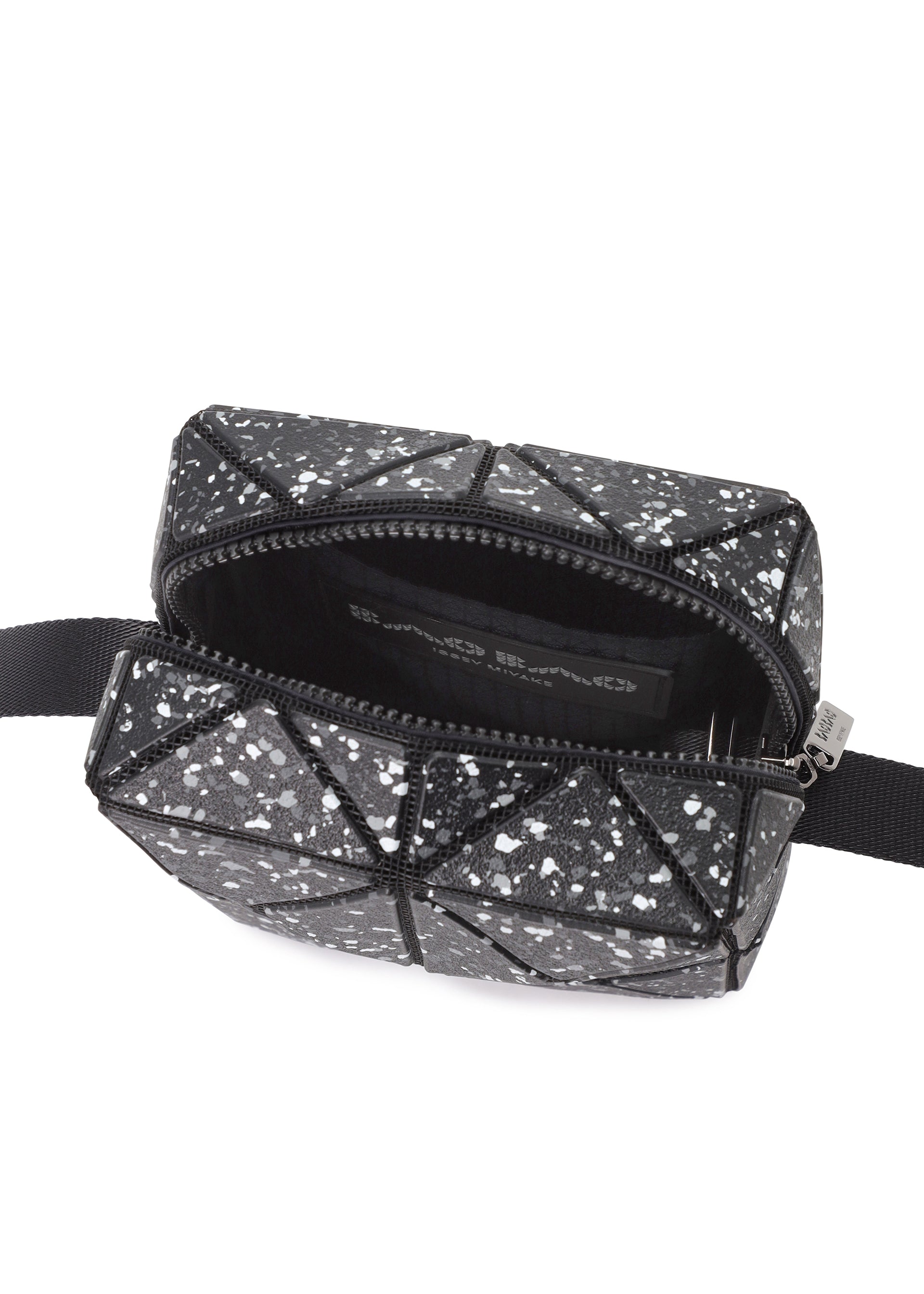 Zoomed view The CITY by BAO BAO ISSEY MIYAKE is a small black geometric shoulder bag with white speckles, a leather-like matte finish, open zipper, black adjustable side straps, and a simple black-lined interior.