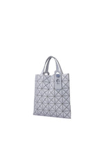 The MINIATURE tote bag by BAO BAO ISSEY MIYAKE displays a geometric silver pattern in leather-like matte material, with two short handles, oversized metal hardware, and a rectangular tag, set against a plain white background.