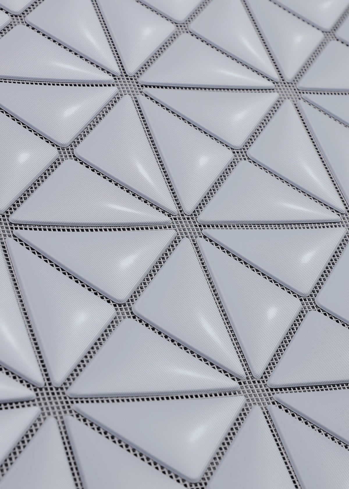 Close-up of the MINIATURE by BAO BAO ISSEY MIYAKE, featuring a geometric grid of raised, glossy white triangular tiles with thin dark lines, evoking modern tote bag hardware. view 6 of 9