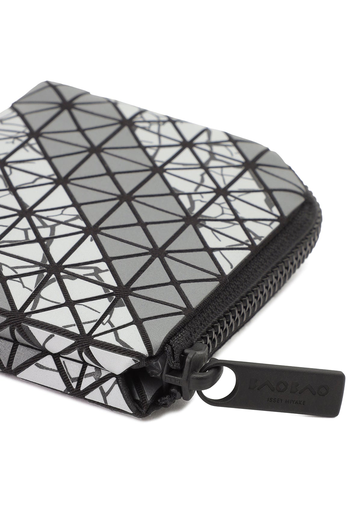 A close-up of the CLAM WALLET AUTOBAHN by BAO BAO ISSEY MIYAKE, featuring a geometric triangle pattern in black, white, and gray with an L-shaped zipper pull. The wallet includes a coin compartment for extra functionality. view 3 of 4