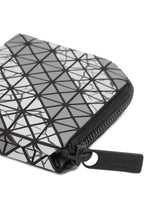 A close-up of the CLAM WALLET AUTOBAHN by BAO BAO ISSEY MIYAKE, featuring a geometric triangle pattern in black, white, and gray with an L-shaped zipper pull. The wallet includes a coin compartment for extra functionality.
