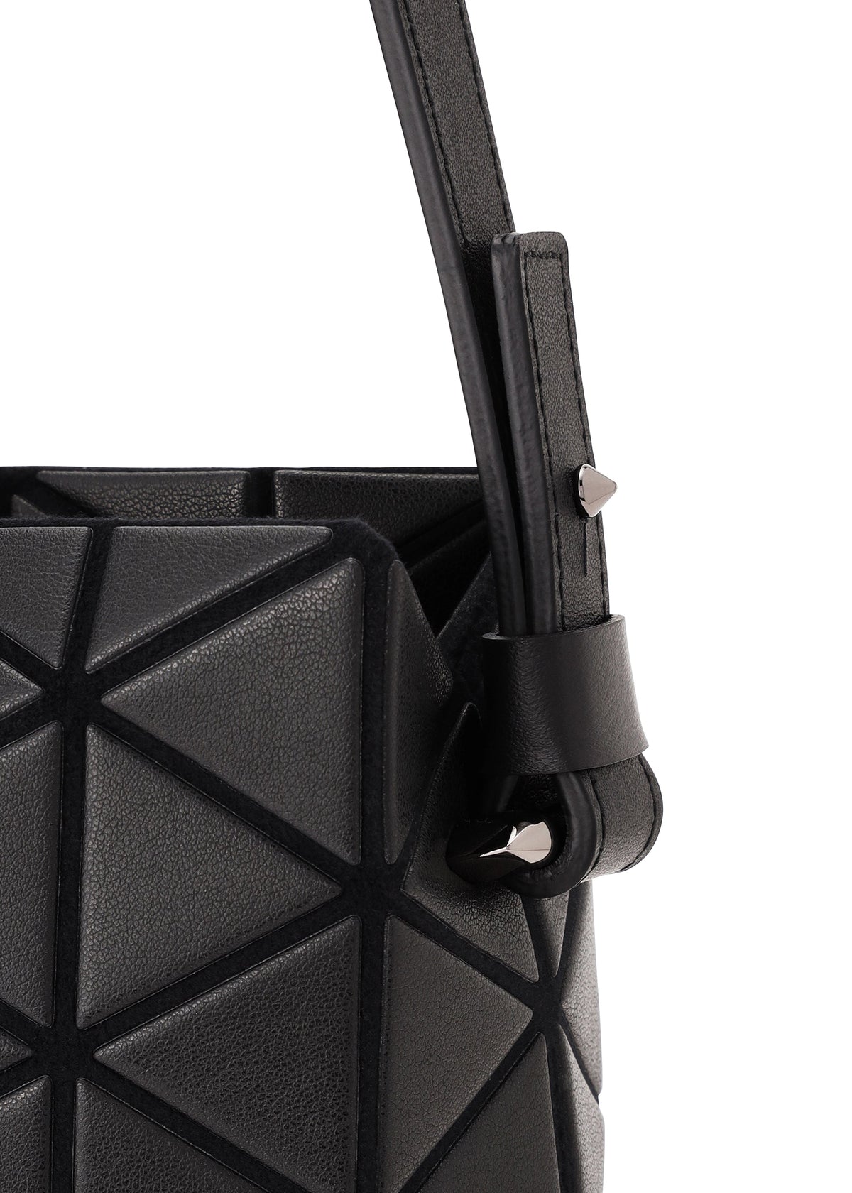 Close-up of the TONNEAU MATTE handbag by BAO BAO ISSEY MIYAKE, showcasing its black geometric-patterned, leather-like surface and angular design, with a strap featuring a silver stud detail that highlights the bag’s unique textures. view 4 of 7