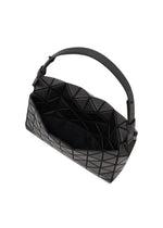 The FOSSETTE by BAO BAO ISSEY MIYAKE is a black handbag featuring a distinctive geometric, triangular pattern, a wide handle, and an open top that reveals a spacious interior secured with a magnetic closure.