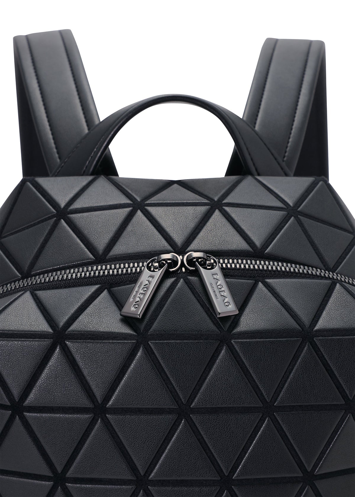 Zoomed view Close-up of the BAO BAO ISSEY MIYAKE HEXAGON backpack in black, featuring geometric triangular panels, two branded zipper pulls, and a front zip pocket on its sleek surface.