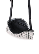 A geometric silver ROW METALLIC shoulder bag from BAO BAO ISSEY MIYAKE, crafted from polarized pearl material with black grid lines, is shown open to reveal its black mesh interior and a visible Bao Bao label.