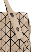 Close-up of the BAO BAO ISSEY MIYAKE ROW METALLIC handbag in beige, showcasing its geometric tote design with black lines forming triangular patterns. The bag features a matching beige strap adorned with round metal accents and is crafted from polarized pearl material for a sophisticated finish.