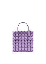 A purple geometric tote bag from the PRISM series, crafted from an enamel-like material, with a grid of black-lined triangles and two handles featuring button details, displayed on a white background.