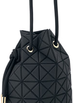 A close-up of the WRING CLAY by BAO BAO ISSEY MIYAKE, a black bucket bag featuring geometric, raised triangular patterns on its nubuck-like surface. Gold grommets and black rope handles accent this edgy drawstring-inspired shoulder bag with a modern design.