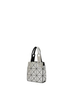 The CARAT handbag by BAO BAO ISSEY MIYAKE is a small, geometric silver and black accessory made from metallic material, featuring two handles and a grid of triangular patterns that showcase its modern, minimalist design. It is displayed against a plain white background.