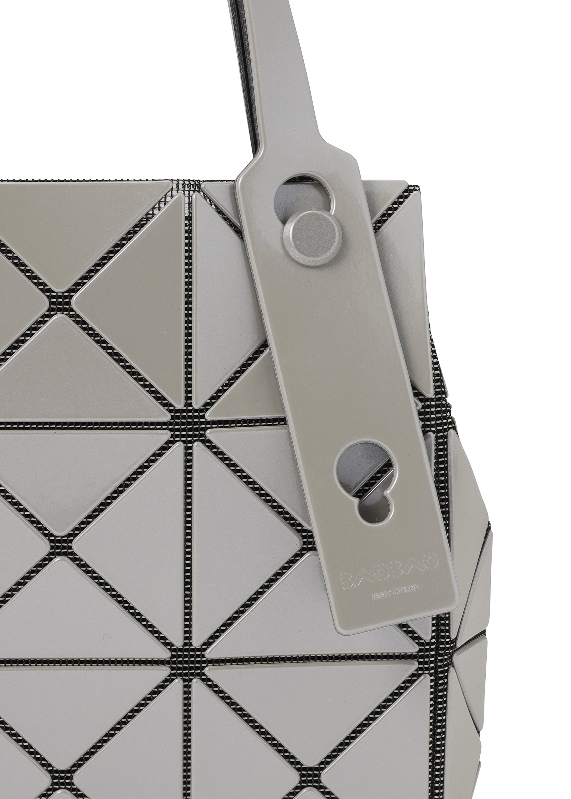 Zoomed view Close-up of the CARAT handbag by BAO BAO ISSEY MIYAKE, showcasing its geometric design with gray triangular panels and black seams, crafted from a sleek metallic material. A matching gray tag with circular cutouts and embossed text is attached to the handle.