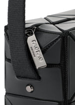 Close-up of the BAO BAO ISSEY MIYAKE CUBOID shoulder bag in black, showcasing its geometric textured triangular patterns and a prominent silver zipper pull engraved with ISSEY MIYAKE. This minimalist leather bag features a wide, adjustable strap secured with a metal stud.