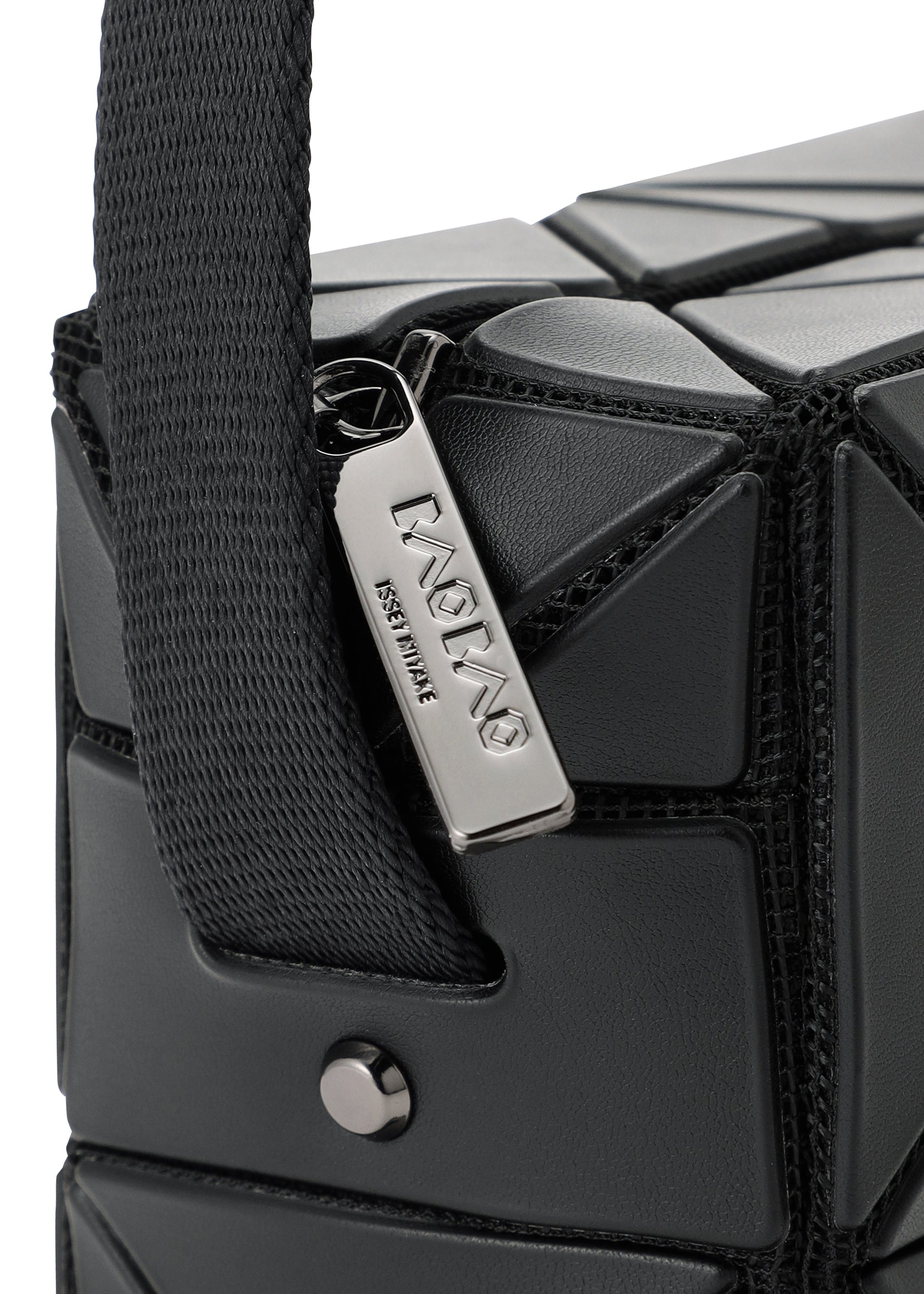 Zoomed view Close-up of the BAO BAO ISSEY MIYAKE CUBOID shoulder bag in black, showcasing its geometric textured triangular patterns and a prominent silver zipper pull engraved with ISSEY MIYAKE. This minimalist leather bag features a wide, adjustable strap secured with a metal stud.
