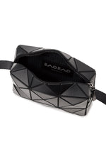 A black CUBOID shoulder bag by BAO BAO ISSEY MIYAKE featuring a geometric, angular design with an adjustable strap. The zipper is partially open, revealing a black fabric interior and a label that reads “BAO BAO ISSEY MIYAKE.”.