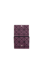 The TWINKLE by BAO BAO ISSEY MIYAKE is a geometric purple bifold wallet with a triangular grid, snap button closure, and compact card holder design, shown open against a white background.