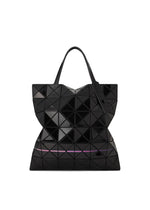 The WARP tote by BAO BAO ISSEY MIYAKE is a black geometric bag made of enamel material with triangular panels, dual handles, a slightly reflective finish, and a subtle rainbow line near the base.
