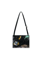 Introducing the COSMIC shoulder bag by BAO BAO ISSEY MIYAKE: a geometric black accessory crafted from sleek enamel, featuring a grid pattern with an abstract design in yellow, blue, and green on the front. It comes with an adjustable strap and is showcased against a white background. - BLACK BASE （no.18）
