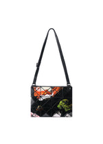 Introducing the COSMIC bag by BAO BAO ISSEY MIYAKE—a rectangular black shoulder bag crafted from enamel material, featuring a grid pattern and vibrant abstract prints in orange, green, pink, and white on the front. It comes with a long, adjustable strap for comfortable carrying.