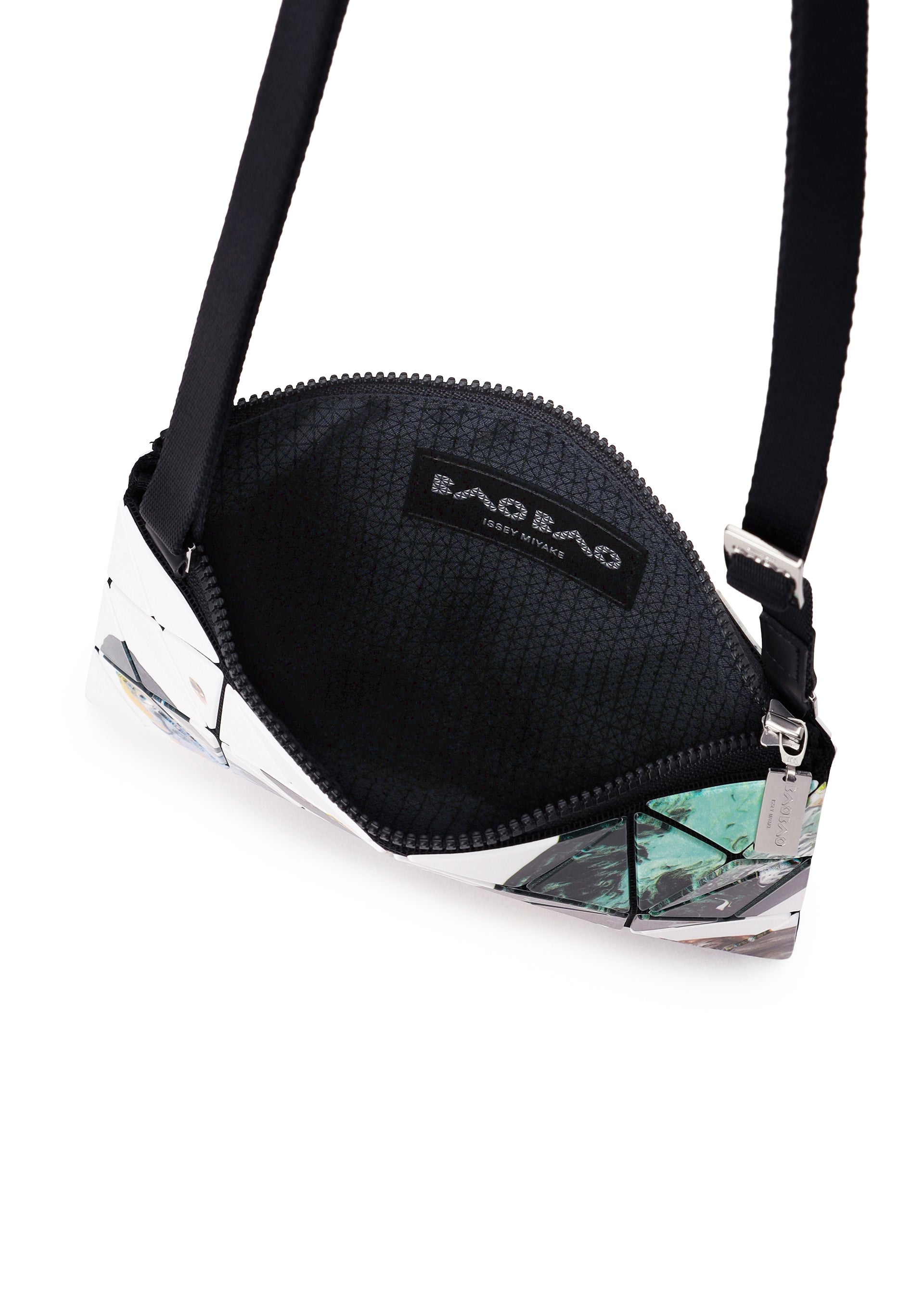 Zoomed view A small BAO BAO ISSEY MIYAKE COSMIC shoulder bag featuring a geometric pattern, black zipper, black adjustable strap, and silver hardware, shown partially open to reveal the textured black interior and brand label inside.