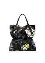 Introducing COSMIC by BAO BAO ISSEY MIYAKE: a modern black geometric tote bag adorned with striking triangle patterns and vibrant abstract designs in yellow, blue, white, and green accents. Crafted from glossy enamel material, this spacious bag features two handles and is perfectly sized to fit A4 documents with ease.