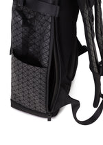 A close-up of the BAO BAO ISSEY MIYAKE HIKER backpack shows its geometric triangle pattern, side pocket, and a partially opened zipper revealing the inner compartment with a laptop pocket.