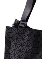 Close-up of the CART MINI by BAO BAO ISSEY MIYAKE, a black mini tote with a strap and buckle, featuring a geometric pattern of triangular shapes for a modern textured look against a white background.