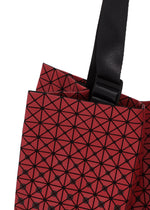 Close-up of the CART GRADUAL tote bag by BAO BAO ISSEY MIYAKE, showcasing its striking red geometric pattern with black lines forming triangles and an adjustable black strap attached at the top—perfect for carrying A4-sized documents.