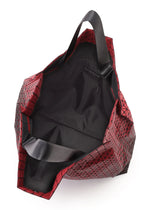 The CART GRADUAL tote bag by BAO BAO ISSEY MIYAKE showcases a striking red geometric pattern and adjustable handles, displayed open to reveal its spacious black-lined interior that comfortably fits A4-sized documents and includes a handy small inner pocket.