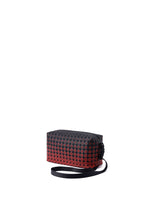 A compact, rectangular shoulder bag from the BAO BAO ISSEY MIYAKE SADDLE BAG GRADUAL series showcases a bold black and red geometric triangular pattern with graphic gradation, finished with a long black strap and set against a white background.