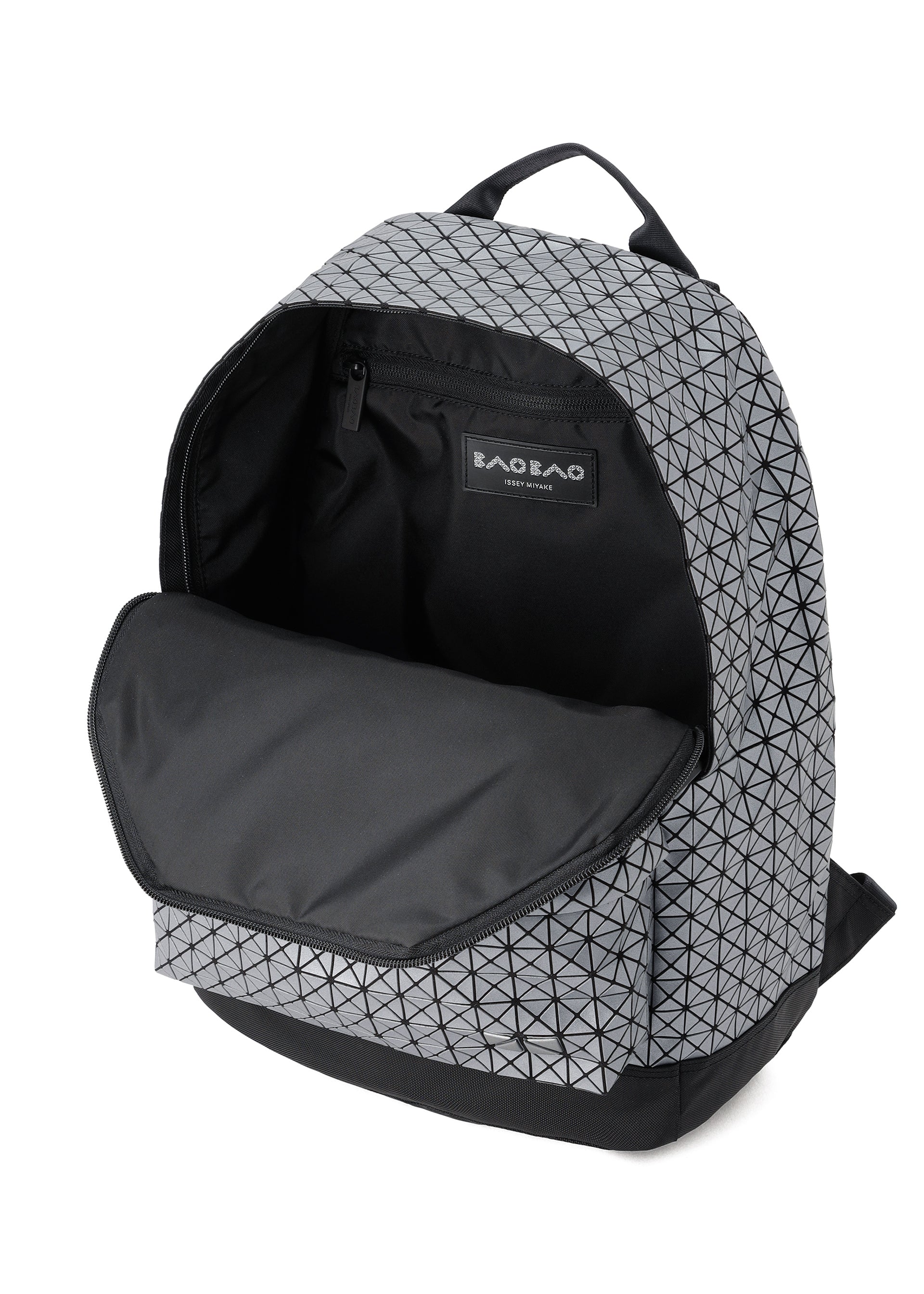 Zoomed view The BAO BAO ISSEY MIYAKE DAYPACK REFLECTOR is a gray backpack with a black geometric pattern, shown open to reveal its spacious main compartment, black interior and zipper, and a visible BAO BAO label inside.