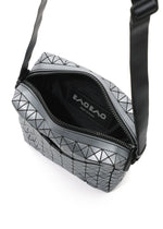 The VOYAGER REFLECTOR by BAO BAO ISSEY MIYAKE is a metallic silver crossbody bag featuring a geometric pattern, black zipper, black interior with label, and also doubles as a chic reflective tote.