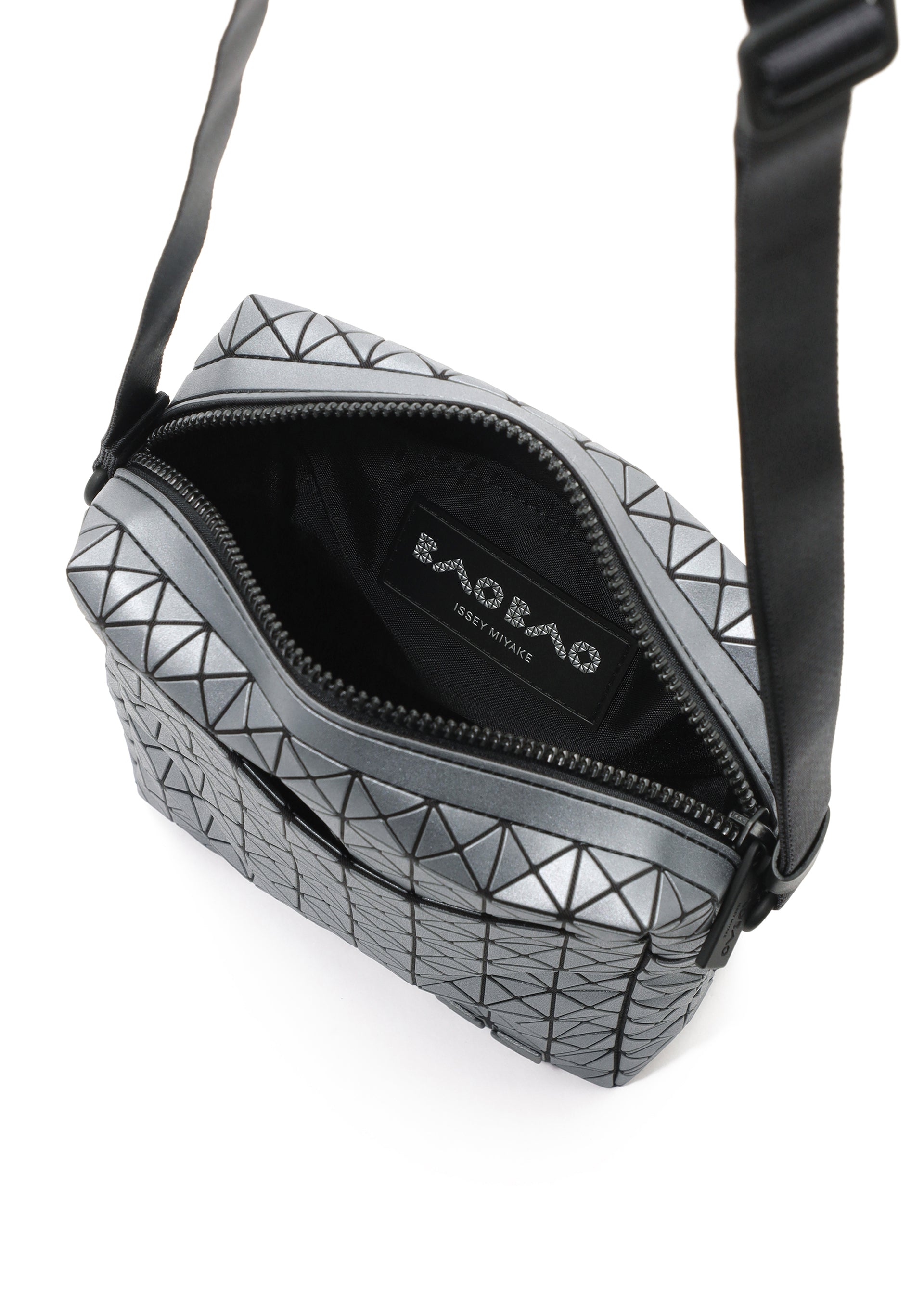 Zoomed view The VOYAGER REFLECTOR by BAO BAO ISSEY MIYAKE is a metallic silver crossbody bag featuring a geometric pattern, black zipper, black interior with label, and also doubles as a chic reflective tote.