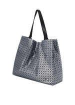 The CART REFLECTOR by BAO BAO ISSEY MIYAKE is a geometric metallic tote bag with a black handle, featuring small triangular shapes for a textured, futuristic design.