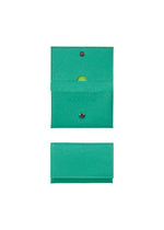 The PACKAGE bifold card case wallet by GOOD GOODS ISSEY MIYAKE is shown open, revealing a small yellow item inside, and closed, both with snap closures and perforated lines—an ideal gift displayed on a white background. - GREEN （no.62）