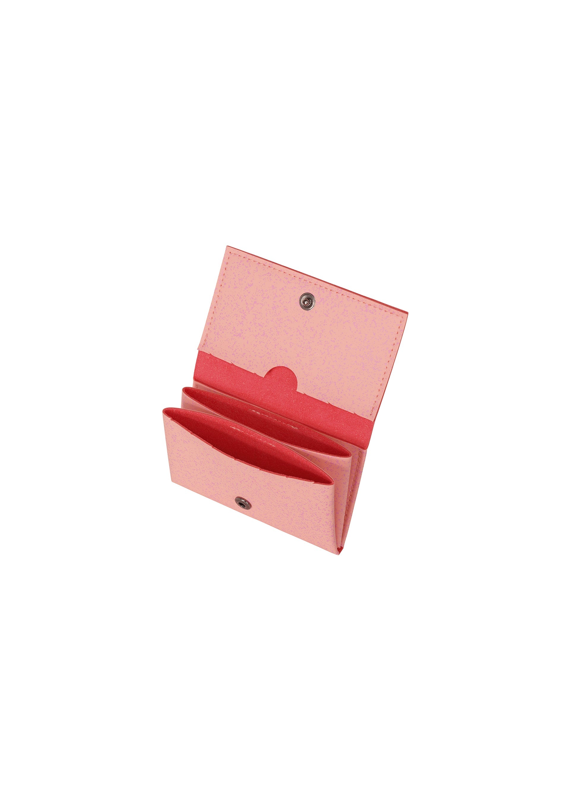 Zoomed view The PACKAGE by GOOD GOODS ISSEY MIYAKE is a pink, rectangular bifold card case with a snap button closure. Open, it reveals two main compartments and perforated lines inside, plus a stylish darker pink lining—ideal for gifting.